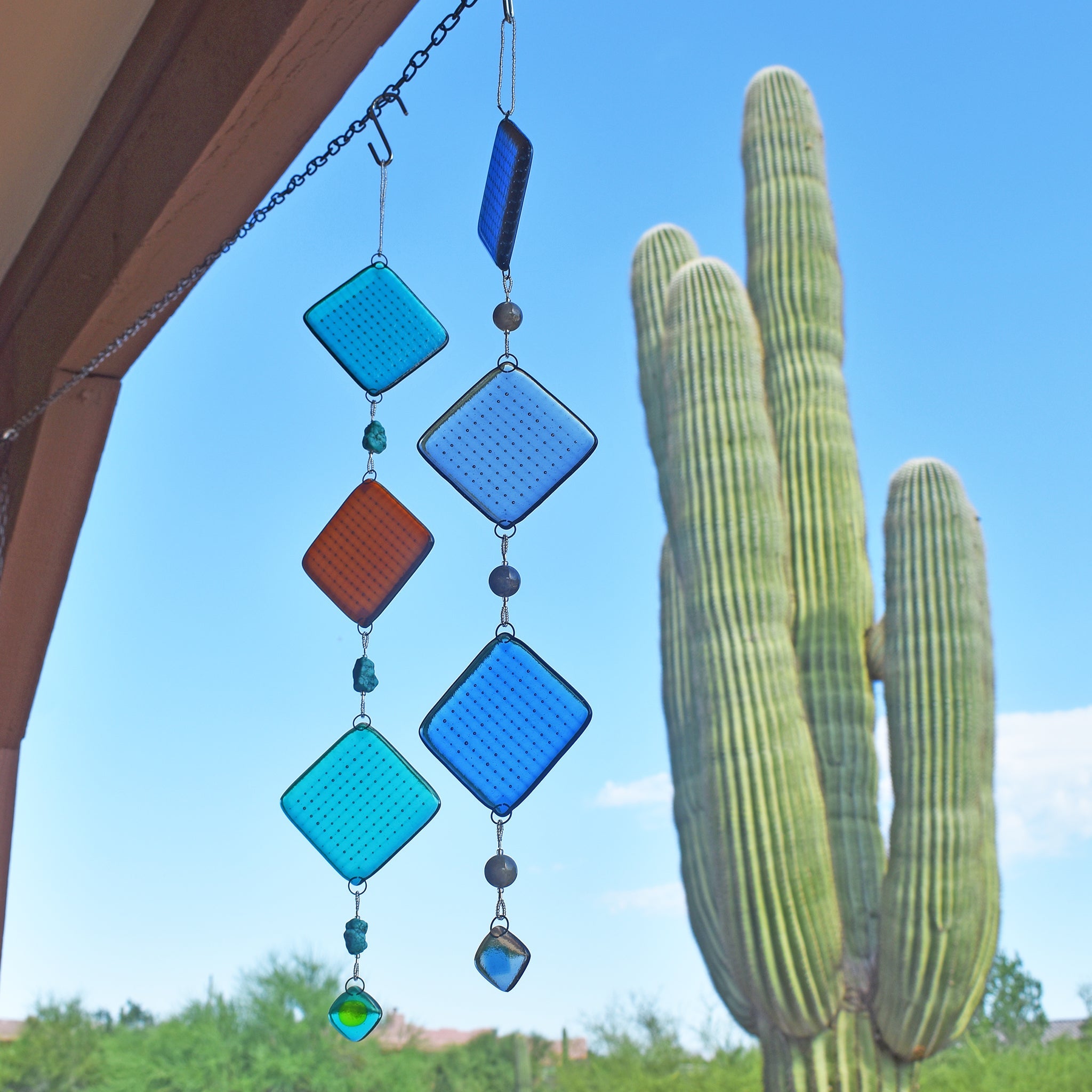 two fused glass sun catchers hanging in patio with saguaro cactus