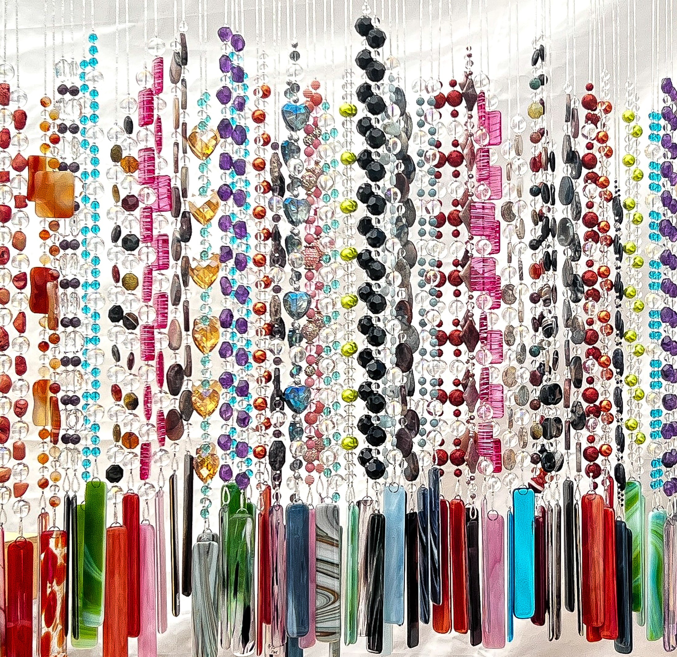 several cinjo handmade wind chimes hanging from chain with ironwood tree and blue sky in background