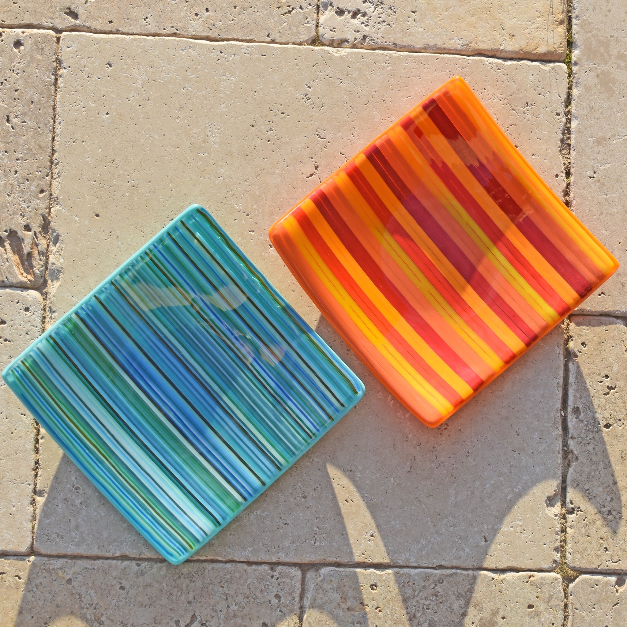 striped fused glass dishes; one contains blue and green stripes; the other contains orange and red stripes