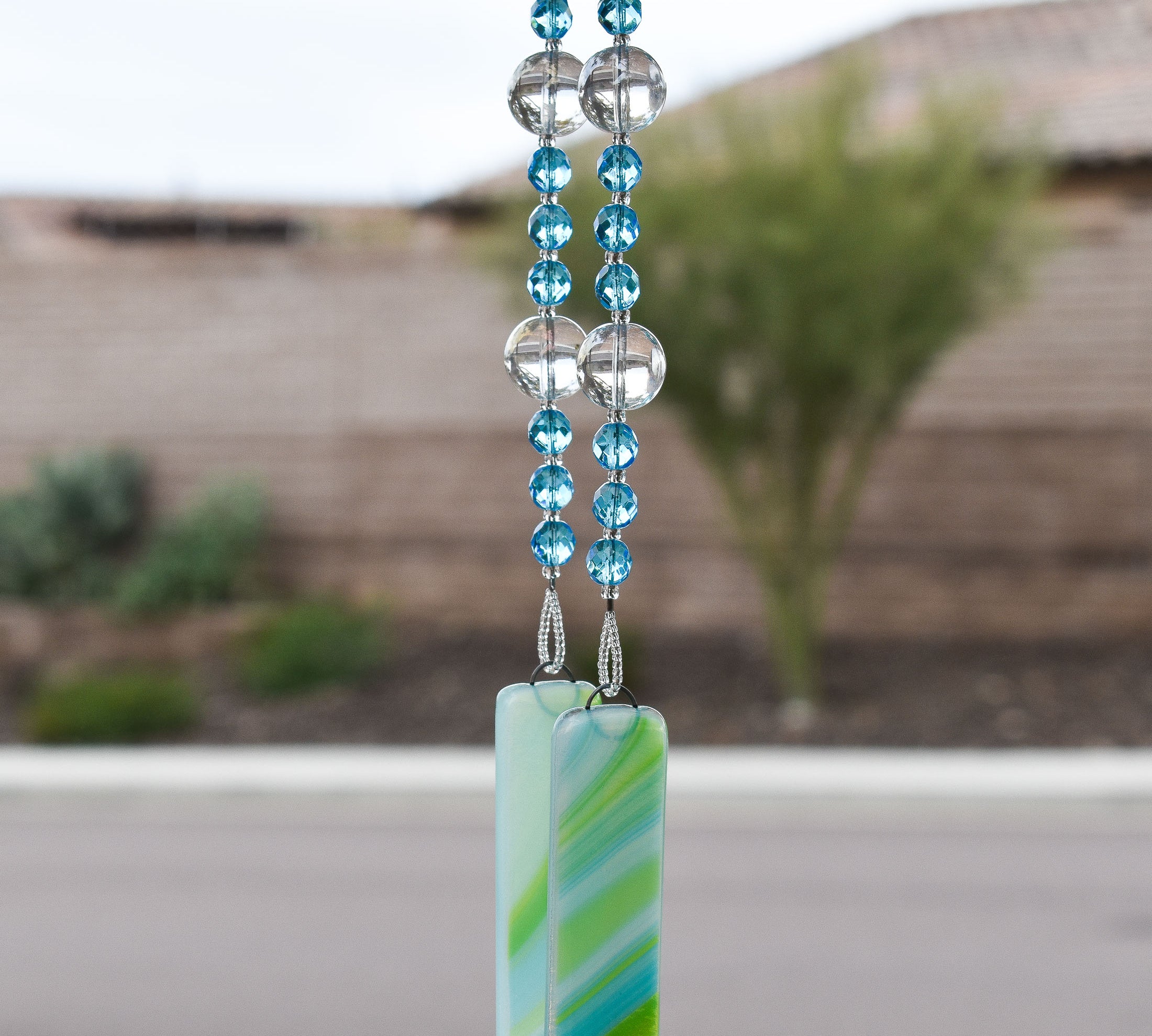 light turquoise glass beads strung with large clear glass lampworked beads, anchored by two piece of blue and green fused glass, hanging vertically 