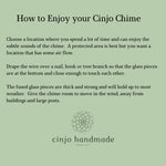 Text on a sage green background reads "How to Enjoy your Cinjo Chime." Instructions advise on chime placement, including air flow and hanging. The Cinjo Handmade logo, featuring a floral design, is at the bottom.