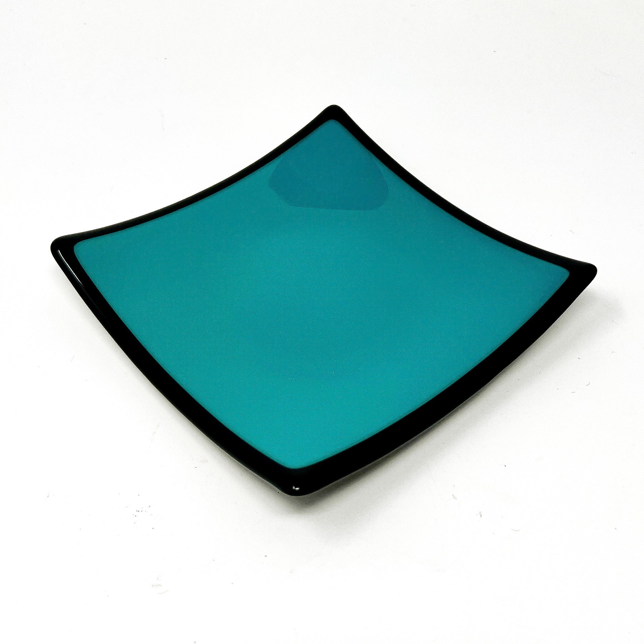 Square glass dish in teal green with black rim in front of white background