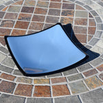 A blue glass plate with black trim and slightly uplifted corners. The plate is sitting on a tiled surface.