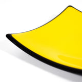 A bright yellow square plate with a black rim. The plate is made of glass and has a slightly curved shape.