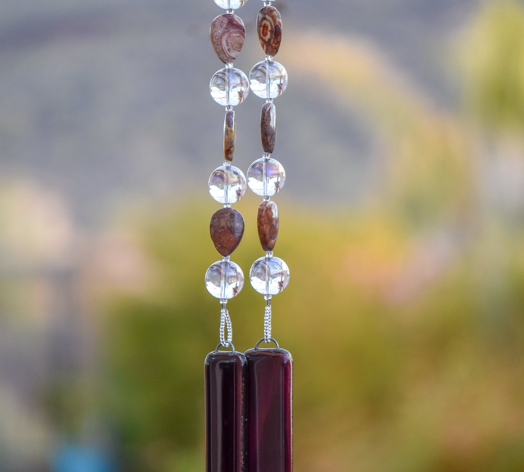 Tear-drop shaped rhyolite stone beads strung with larger clear glass beads, hanging tree tree, anchored by two pieces of dark purple fused glass