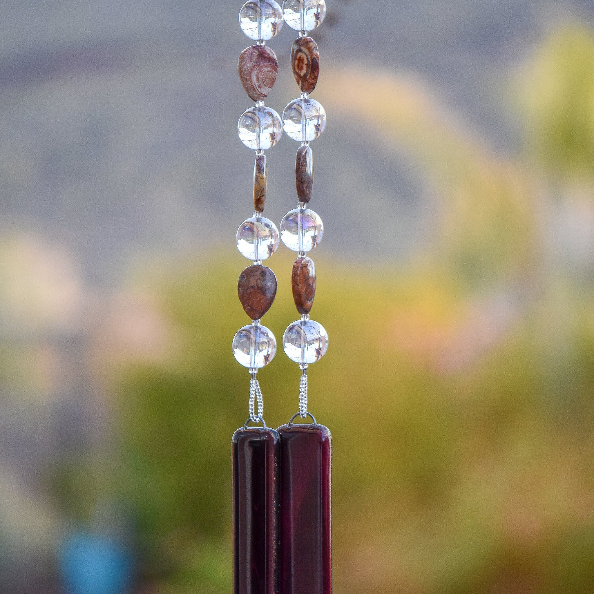 Tear-drop shaped rhyolite stone beads strung with larger clear glass beads, hanging tree tree, anchored by two pieces of dark purple fused glass