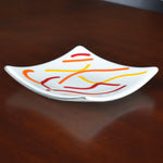 Six inch square dish in creamy white with abstract design of orange, red and yellow fused glass