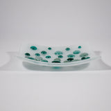 Pure white square glass dish with round glass pebblest; in various shades of teal green. Tray is 6 inch square with sloped corners.