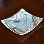 Large 12&quot; glass tray on wood table. Tray is white with swirl pattern in gray, tan and aqua, embellished with flecks of cream and aqua glass. Display as art or use as centerpiece or serving tray.