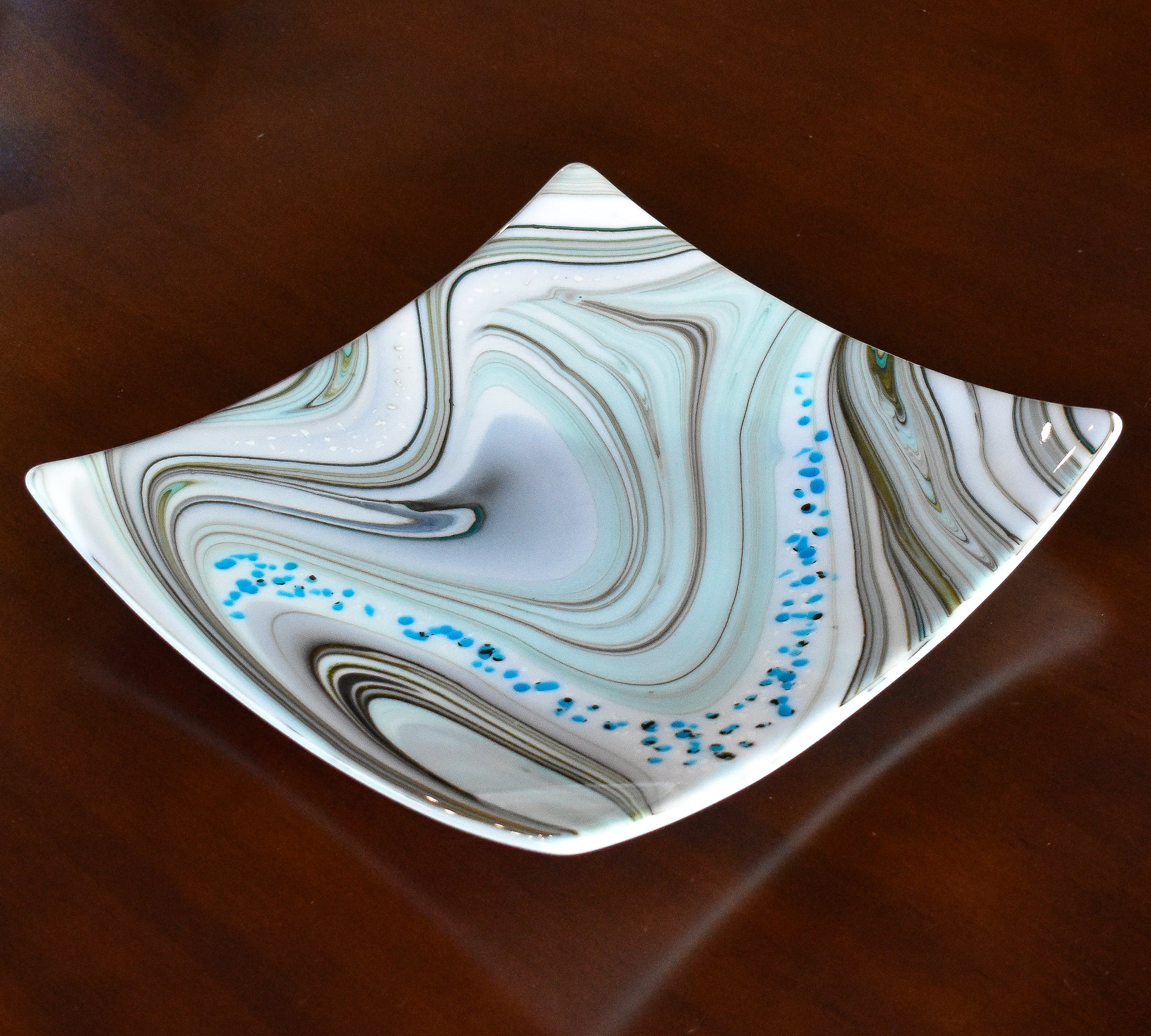 Large 12&quot; glass tray on wood table. Tray is white with swirl pattern in gray, tan and aqua, embellished with flecks of cream and aqua glass. Display as art or use as centerpiece or serving tray.