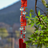 Large red and white rectangular acrylic beads paired with reflective clear glass beads and smaller red glass beads, anchored by opaque red glass, hanging from tree