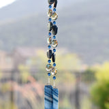 Blue agate slice beads strung with blue and silver glass beads, hanging vertically, anchored by two pieces of fused glass.