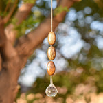 Three oval iron jasper stones strung on wire, hanging vertically, anchored by round crystal pendant.