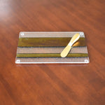 Rectangular cheese tray made with gold, black and clear iridescent fused glass. Gold spreader knife laying on top.