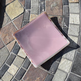 Lavender-colored square glass trinket tray on stone table