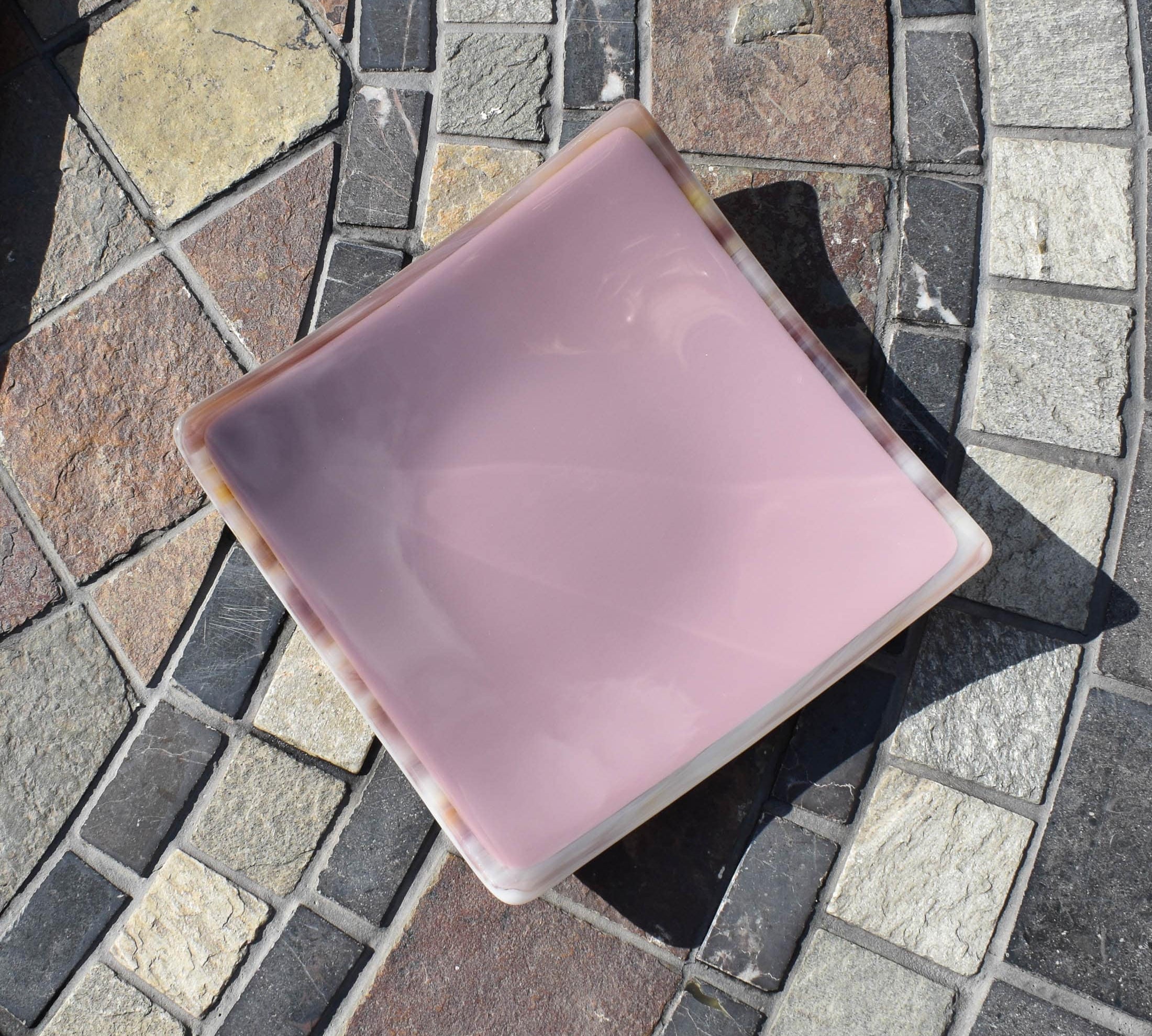 Lavender-colored square glass trinket tray on stone table