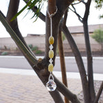 Three carved jade barrel beads flanked by crystal beads and anchored by crystal prism, hanging from tree.