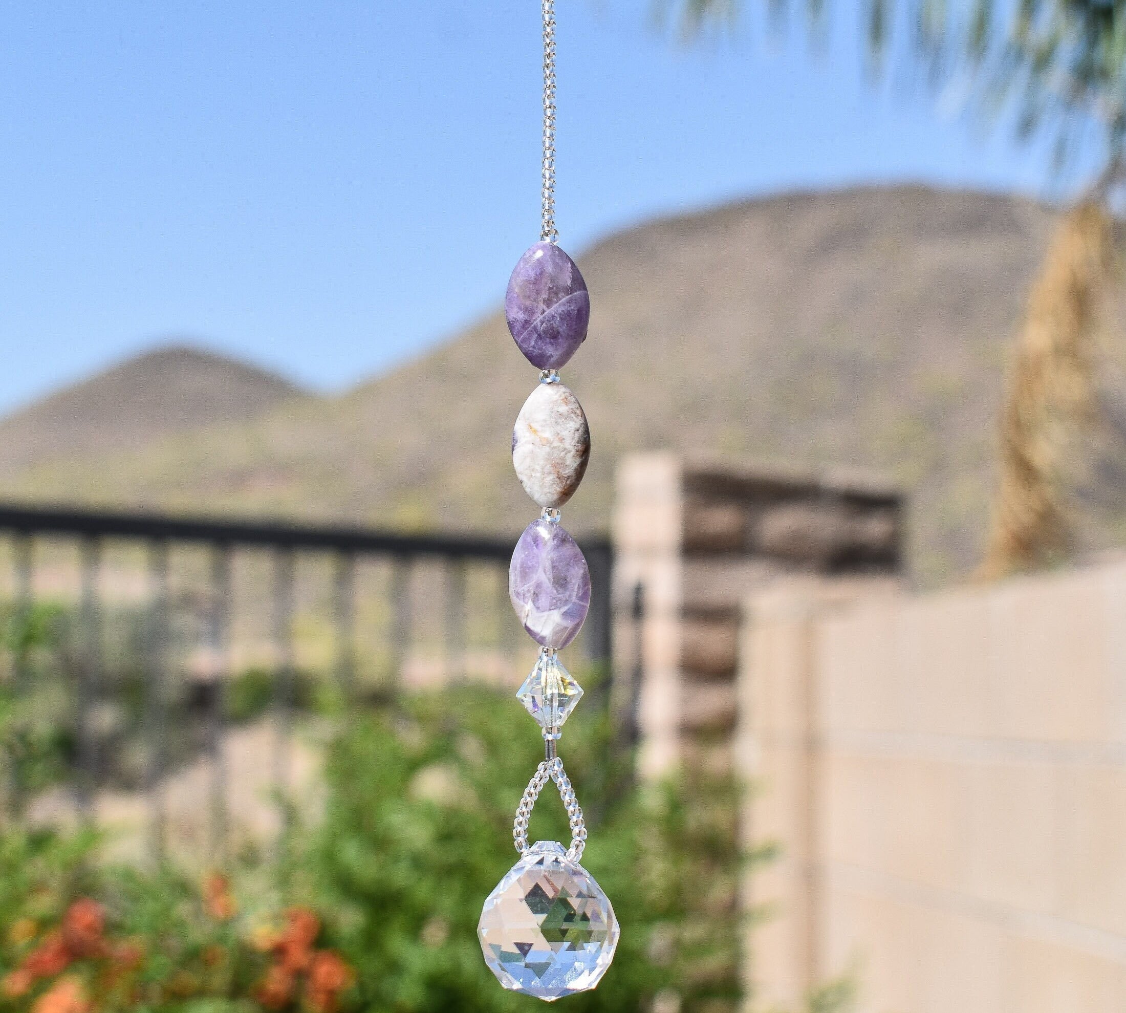 Three amethyst stone beads strung with crystal, hanging vertically, anchored by round crystal prism.