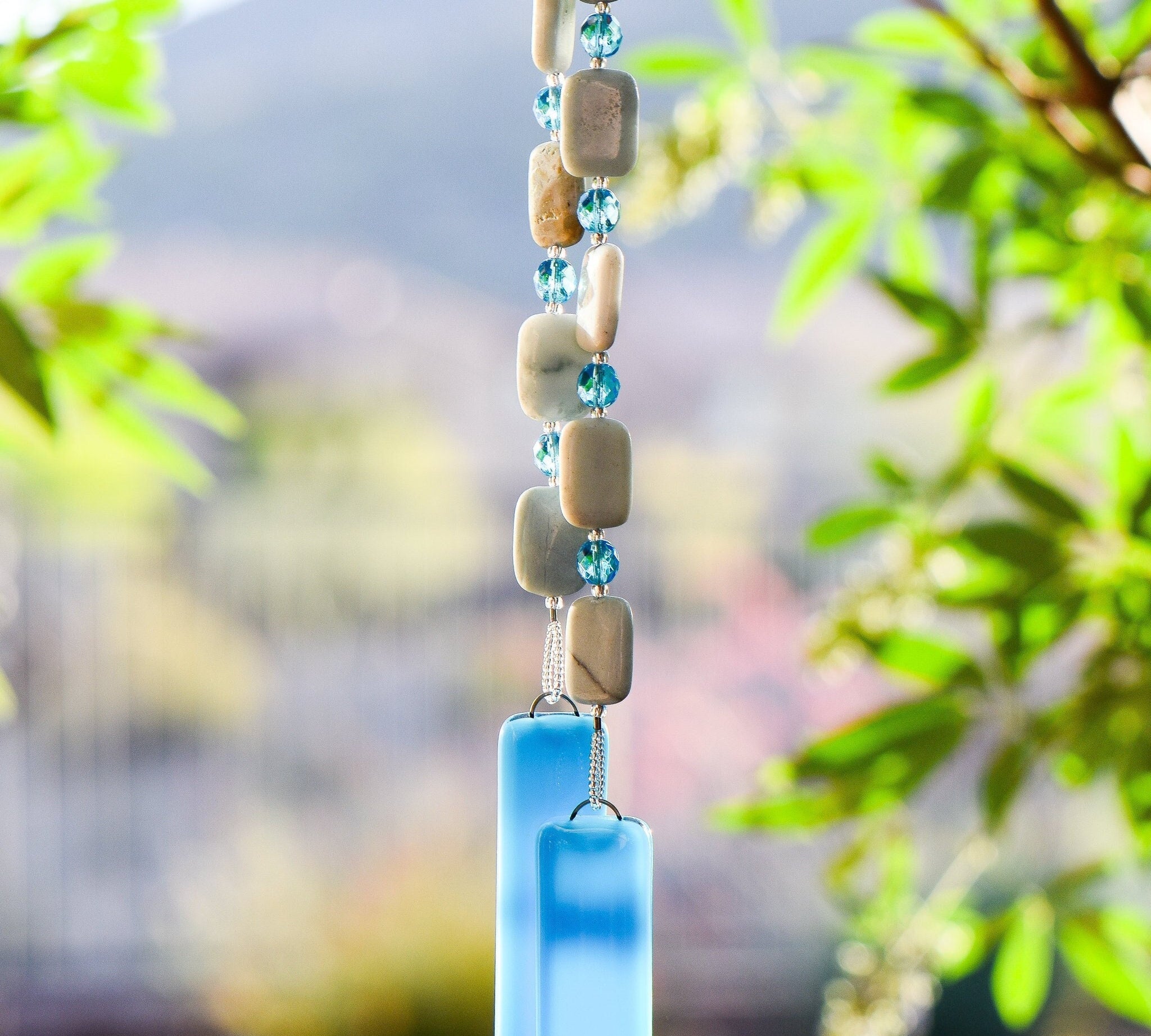 Rectangular Amazonite stone beads strung with turquoise blue crystal beads, hanging vertically from tree with two pieces of turquoise blue glass at bottom.