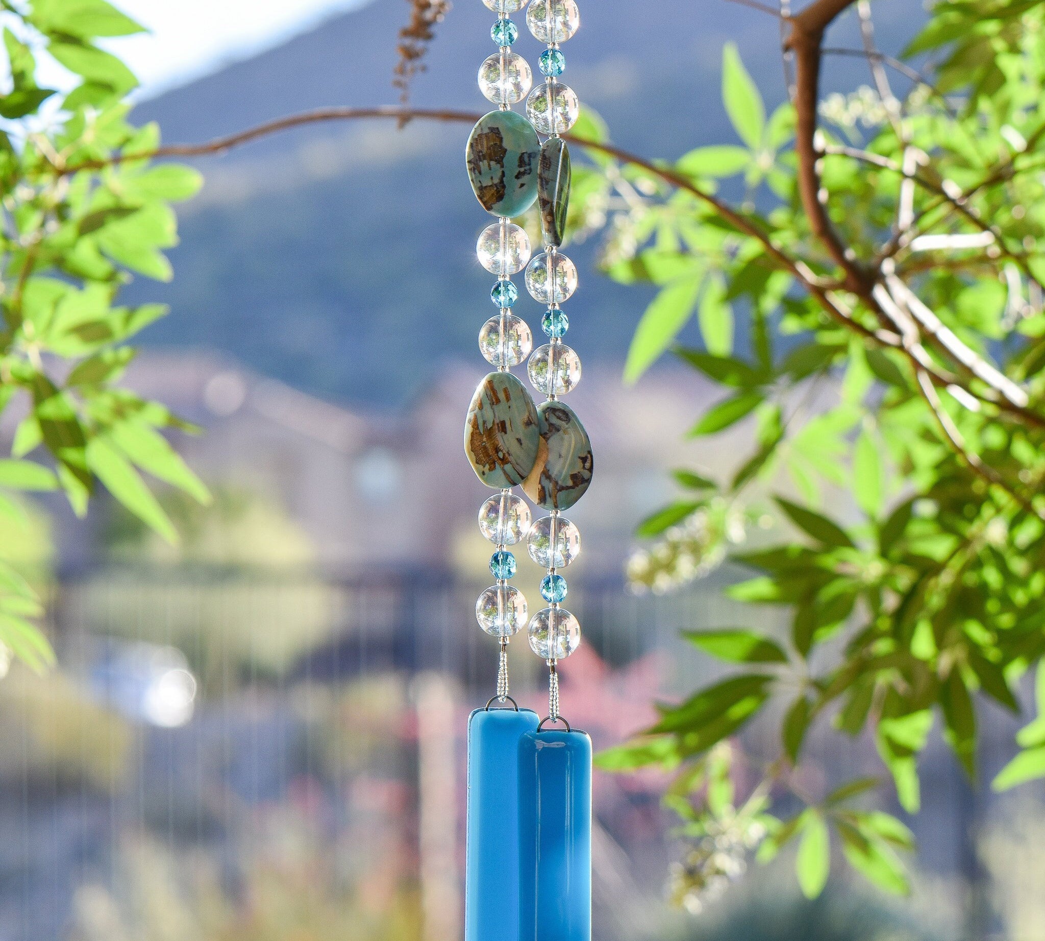 Large dragon skin agate stone beads paired with clear and turquoise blue glass beads hanging vertically from tree with two pieces of turquoise blue fused glass as anchors.