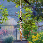 Large black agate slice beads and very large onyx beads strung with smaller clear and black onyx beads, hanging vertically from vitex tree with brown and black translucent fused glass anchors.