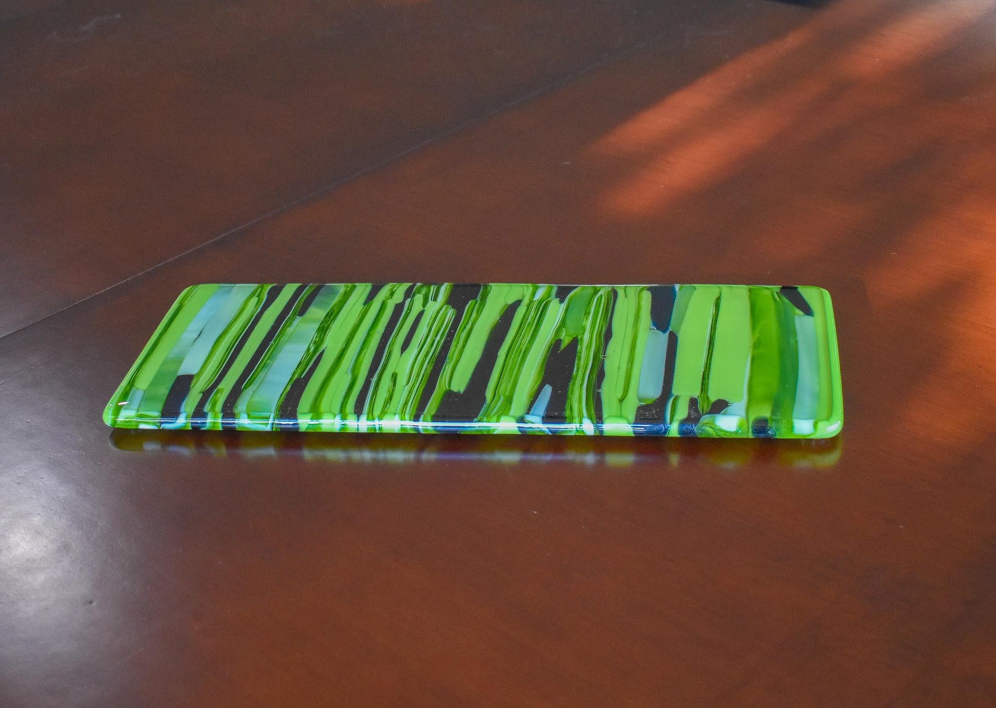 Rectangular glass cheese tray made of strips of lime green, amazon green and navy blue glass.