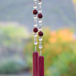 Large cranberry red jade stones beaded with glass and crystals, anchored by two pieces of pink fused glass, hanging vertically.