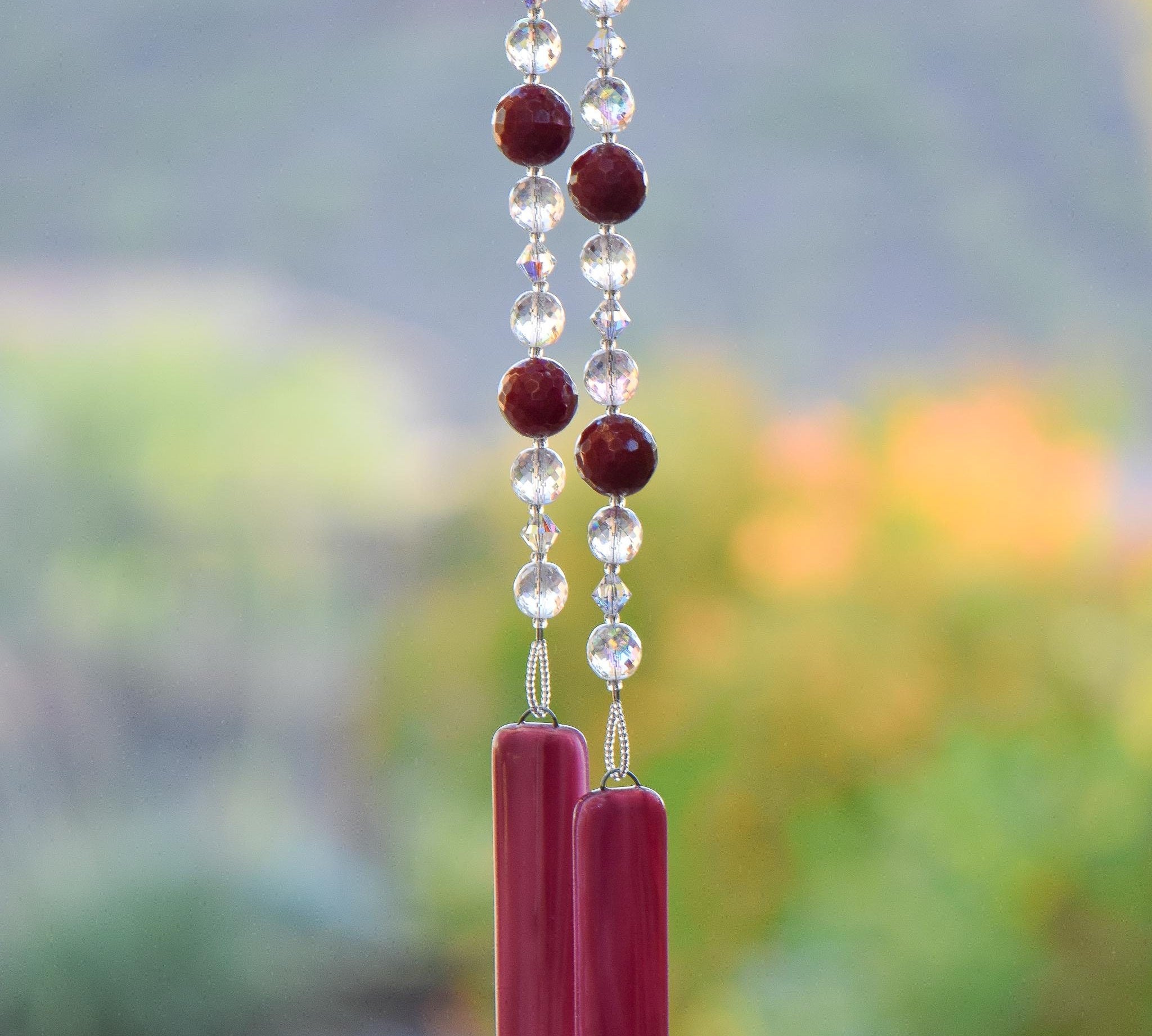 Large cranberry red jade stones beaded with glass and crystals, anchored by two pieces of pink fused glass, hanging vertically.