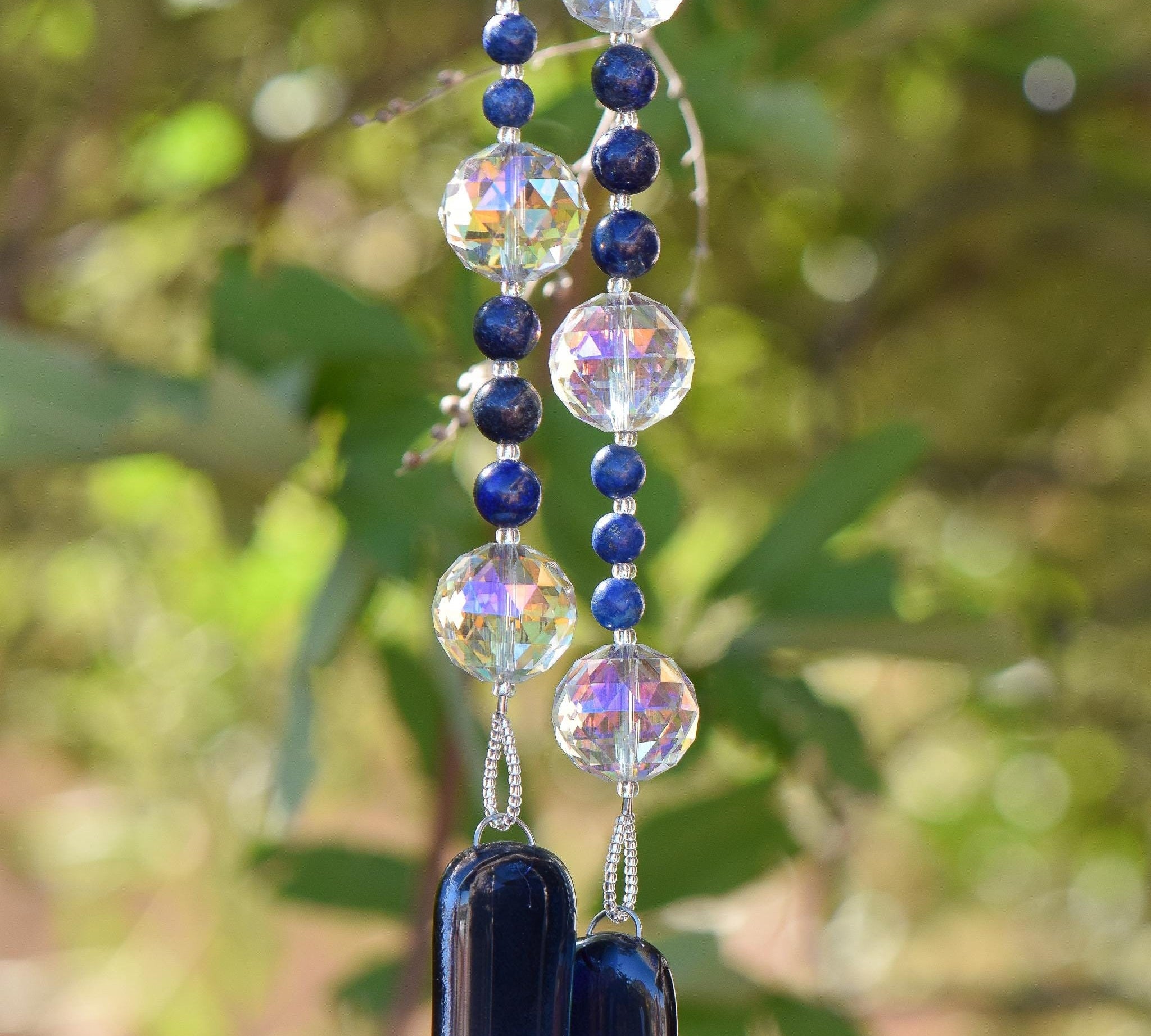 Large glass crystal beads strung with two sizes of small lapis lazuli stone beads, hanging vertically, anchored by two pieces of navy blue fused glass.