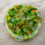 Large, round, glass platter made of green, orange and yellow glass