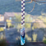 Purple glass pearl beads paired with large clear glass beads hanging vertically, anchored by two pieces of kiln-formed glass in aqua, purple and white