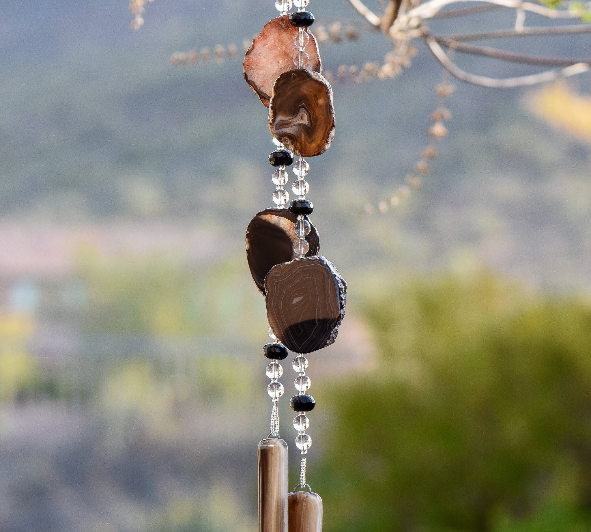 Large black agate geode slices strung with black onyx and clear glass, hanging vertically, anchored by two pieces of black and brown glass.