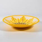 Round glass bowl with hand-painted sunflower design and bright yellow trim on wood table