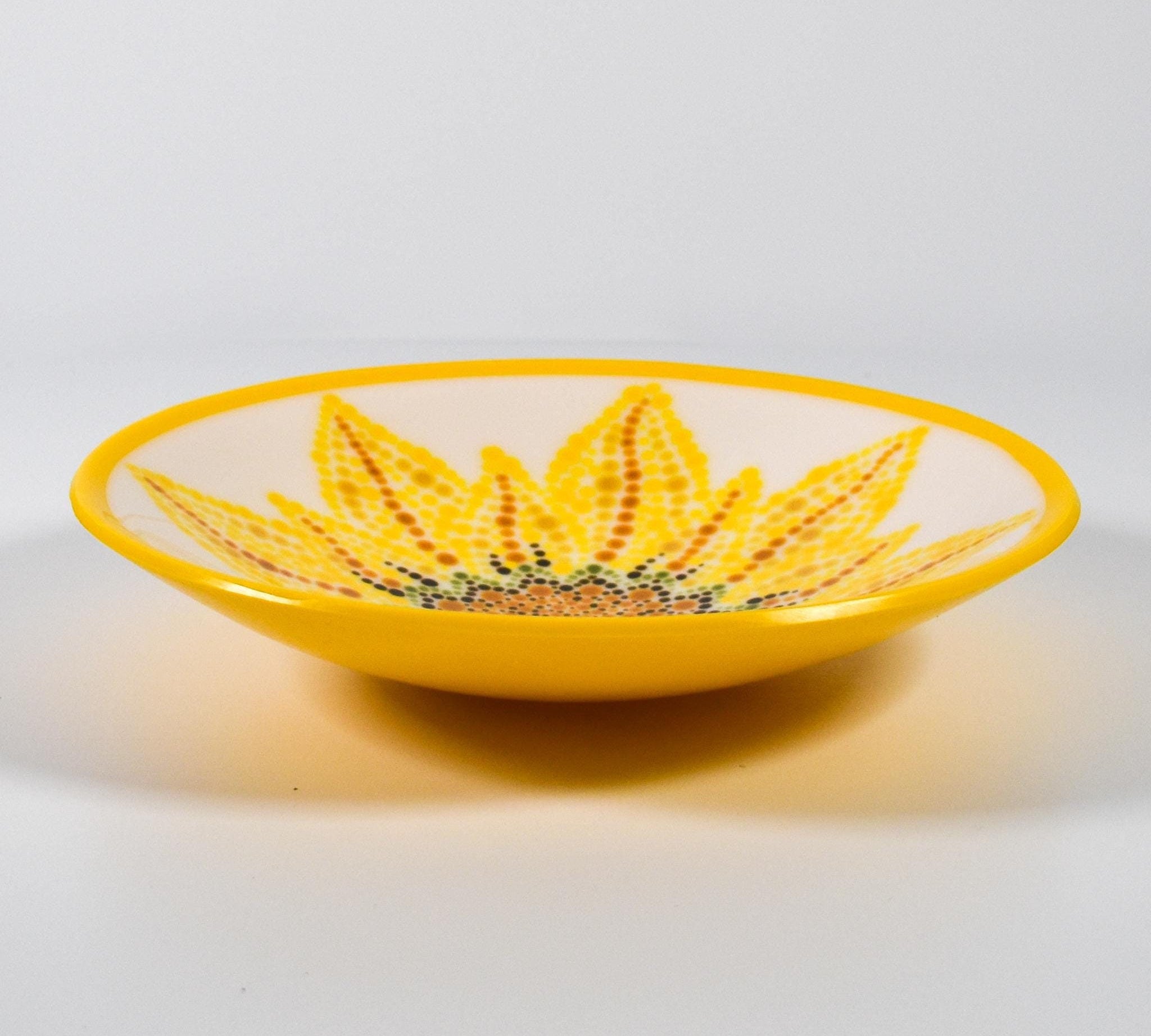 Round glass bowl with hand-painted sunflower design and bright yellow trim on wood table