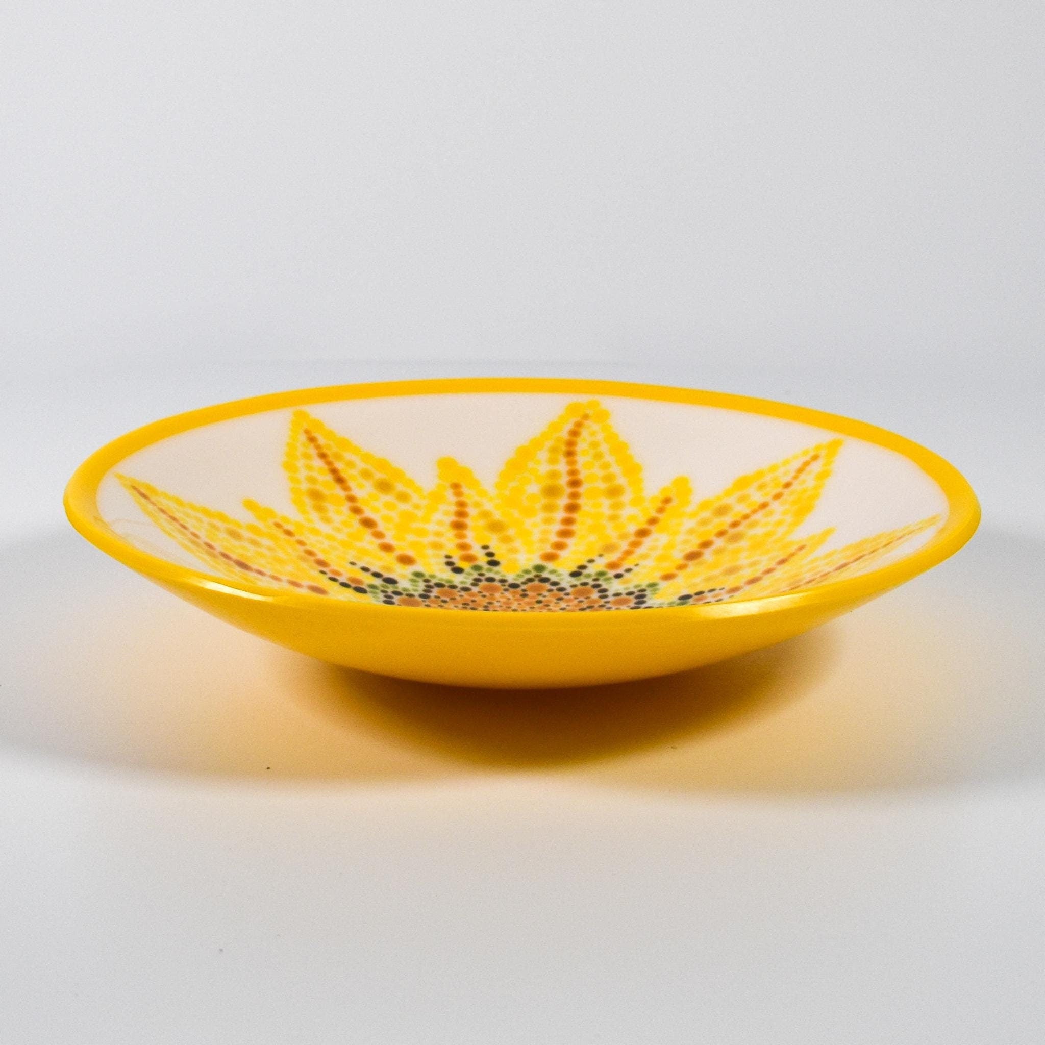 Round glass bowl with hand-painted sunflower design and bright yellow trim on wood table