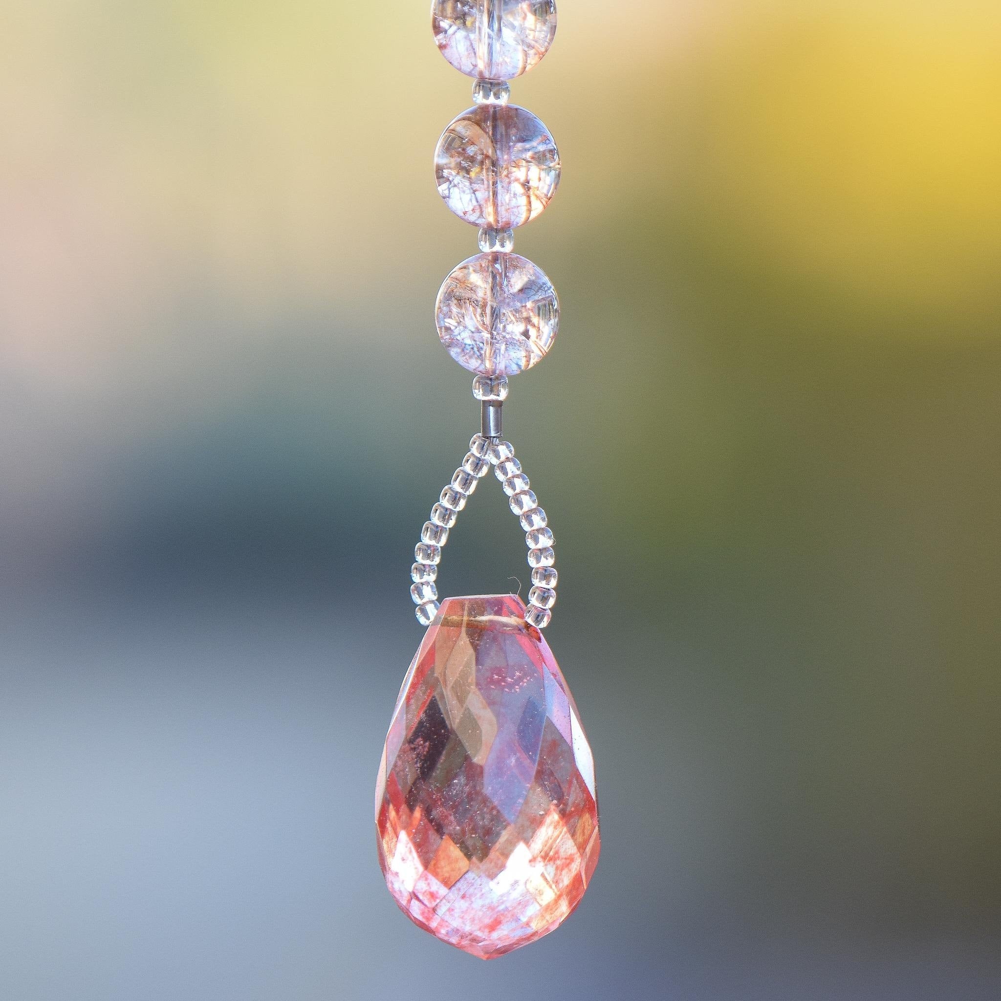 Large faceted pink stone pendant paired with crackle glass beads in a blush pink, hanging vertically in small sun catcher