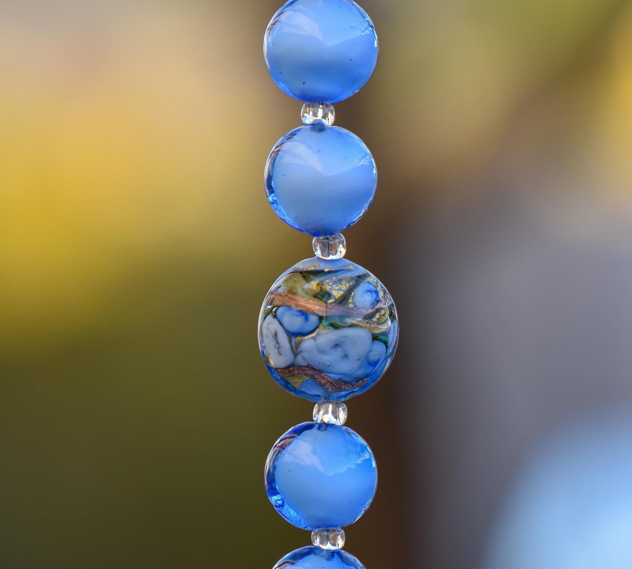 Puffed round murano glass bead in blue with gold and silver foil surrounded by pure blue murano glass beads in this small sun catcher.