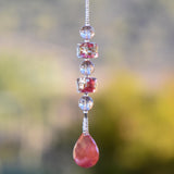 Small pink and gold sun catcher hanging vertically against blurred background, made with Murano glass beads and a stone pendant