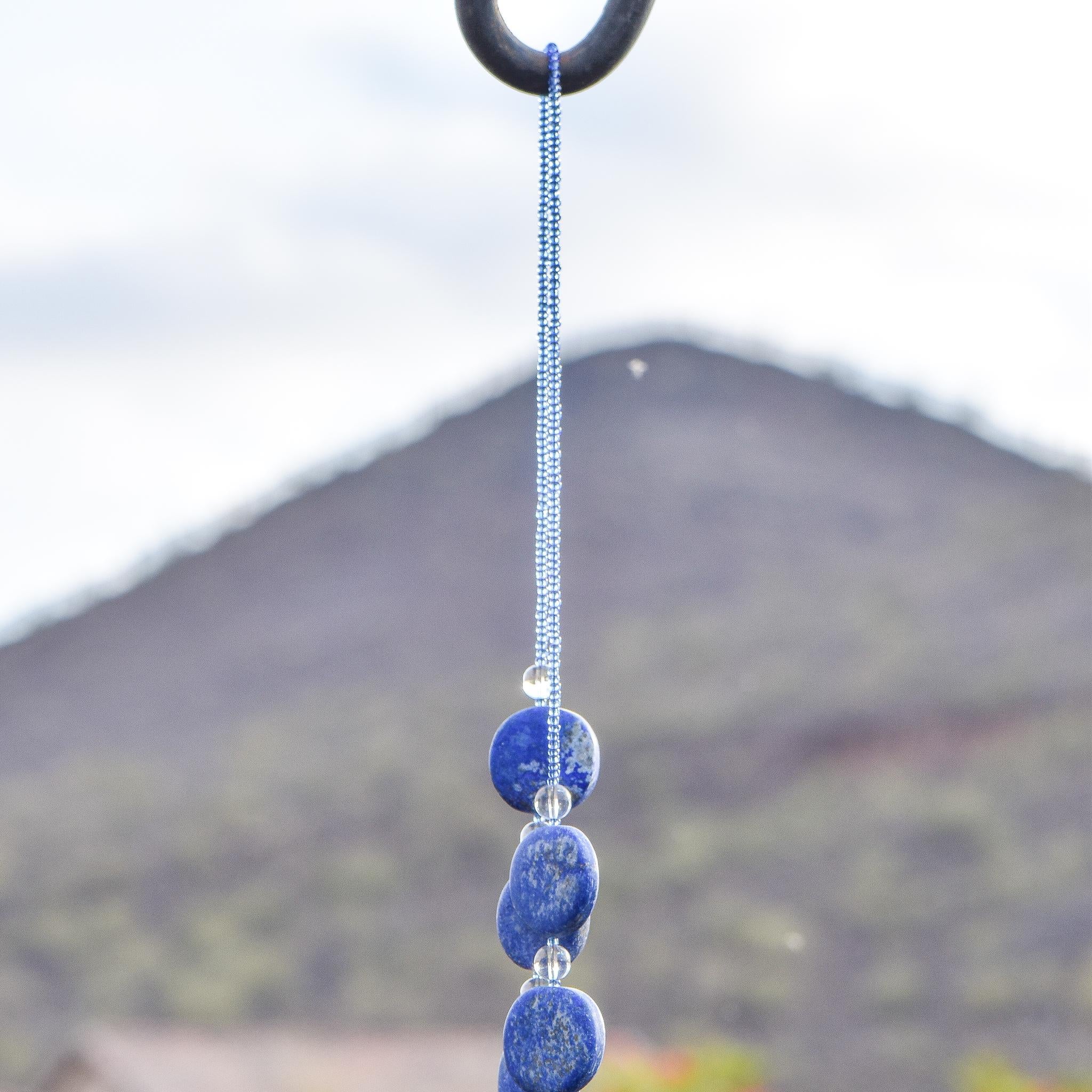 Wire covered in transparent blue seed beads, draped over shepherds hook against mountain background.