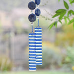Two pieces of clear glass with transparent blue stripes are anchoring wire beaded with large lapis lazuli stones.
