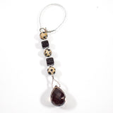 Small beaded sun catcher made with two black cube beads, three round tan beads with black spots and a large smoky quartz faceted tear drop pendant, hanging vertically against white background.