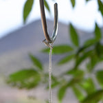 Silver plated clasp being used to wrap beaded wire around a hanging hook.