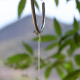 Silver plated clasp being used to wrap beaded wire around a hanging hook.