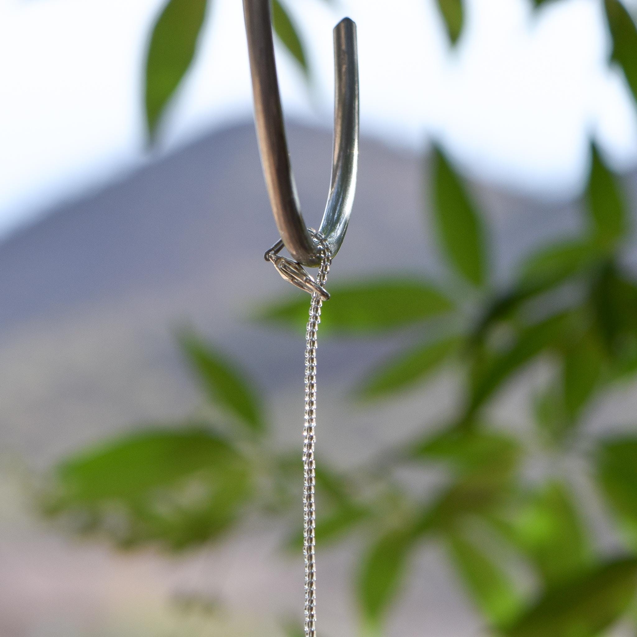 Silver plated clasp being used to wrap beaded wire around a hanging hook.
