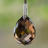 Large, faceted smoky quartz pendant hanging from beaded wire.