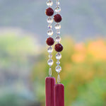 Large cranberry red jade stones beaded with glass and crystals, anchored by two pieces of pink fused glass, hanging vertically.
