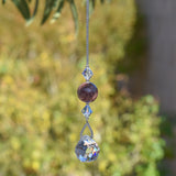 May include: A crystal suncatcher with a silver chain, a clear crystal ball, and a purple and gray stone bead.