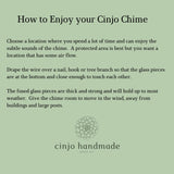 Instructions on how to enjoy a Cinjo Chime. The text is on a light green background. It advises choosing a location with air flow, draping the wire over a nail or branch, and giving the chime room to move. The Cinjo handmade glass art logo is at the bottom.