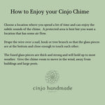 Written description of how to enjoy your Cinjo Chime, including choosing a place away from heavy structures and draping the wire over a nail, hook or tree branch. Cinjo Handmade logo is at the bottom.