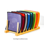 Several square fused glass trays in various colors lined up on a wooden plate stand.